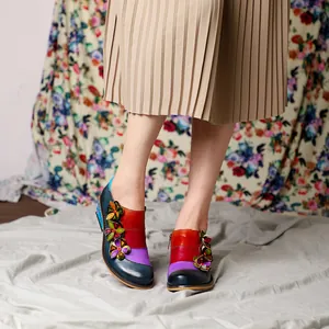Detail of retro color-block leather shoes with handmade floral accents and side zipper.
