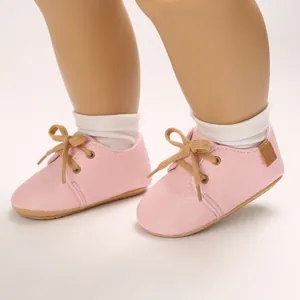 Detailed view of pink infant walking shoes with soft soles and tan laces.