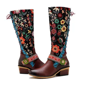 Detailed view of ethnic floral embroidery and lace-up design on knee-high leather boots