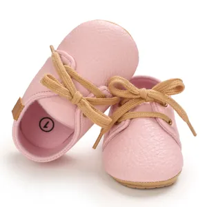 Detailed view of pink faux leather baby walker shoes with soft rubber soles and laces.
