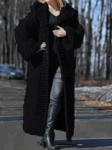 Full view showing the chunky texture and long length of the black hooded knit cardigan outdoors.
