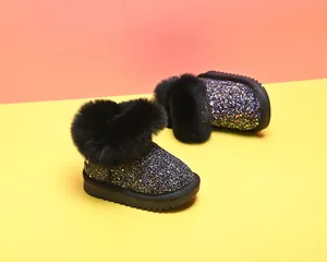 Nahaufnahme glitzernder schwarzer Baby-Schneestiefel mit Kunstfellbesatz und dicken Sohlen