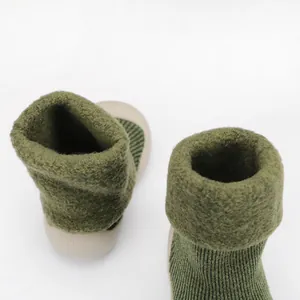 Primo piano di scarpine da bambino in maglia verde calda con suole morbide e fodera in peluche