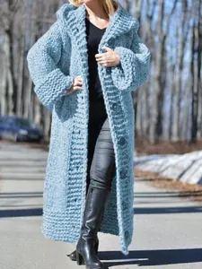 Full-length lifestyle view of a light blue chunky knit oversized hooded cardigan