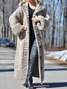 Close-up view of a cozy chunky knit long hooded cardigan worn by a model outdoors