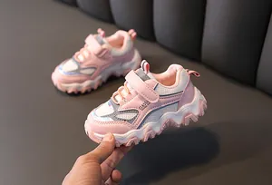 Close-up van roze en witte kindersportschoenen met zachte zolen en klittenband