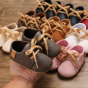 Detailed view of brown faux leather baby walking shoes with soft soles and laces
