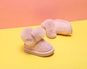 Nahaufnahme von rosa glitzernden Babystiefeln mit flauschigem Kunstpelzbesatz.