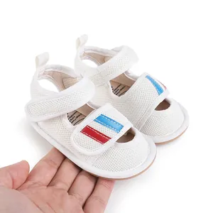 Breathable white mesh baby walking shoes with red and blue stripes, shown for scale.