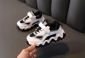 Close-up van modieuze zwart-witte kindersneakers met zachte, golvende zolen voor kinderen