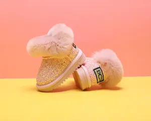 Detailaufnahme von pinkfarbenen Glitzer-Babystiefeln mit weichem Kunstfellbesatz