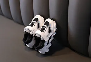 Close-up van stijlvolle witte kindersneakers met regenboogdetails en klittenband.