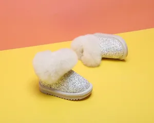 Nahaufnahme von Glitzer-Babystiefeln mit weißem Kunstpelzbesatz für kleine Mädchen
