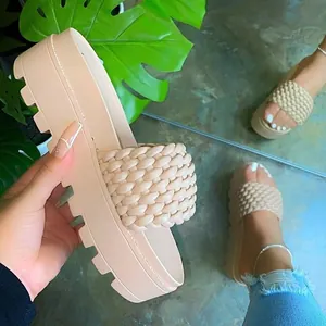Close-up of beige platform sandals featuring a stylish woven strap and thick lug sole.