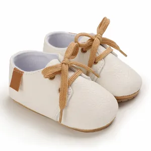 Close-up of white infant walking shoes with soft rubber soles and tan cotton laces