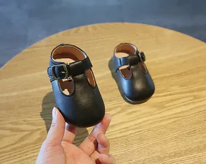 Detailaufnahme von schwarzen T-Steg-Lauflernschuhen aus Leder mit weicher Sohle für Babys