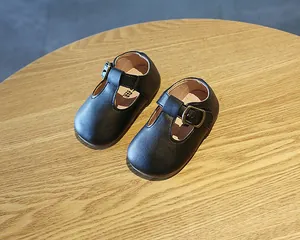 Nahaufnahme schwarzer Baby-T-Steg-Lederschuhe mit Vintage-Schnalle auf Holz