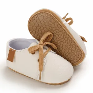 Close-up of white soft-sole baby walking shoes with brown laces and anti-slip sole