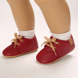Close-up detail of red faux-leather infant walking shoes with soft rubber soles and laces
