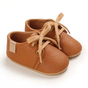 Detailed view of brown faux leather baby walking shoes with soft rubber soles and laces
