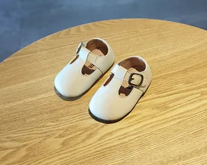 Nahaufnahme von klassischen weißen Baby-T-Steg-Lederschuhen auf einem Holztisch