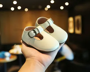 Nahaufnahme von cremefarbenen Baby-Leder-T-Steg-Schuhen mit Vintage-Schnalle
