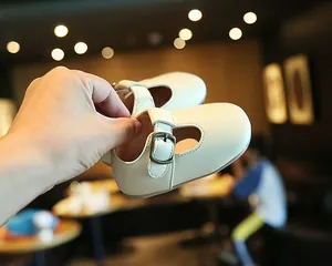 Nahaufnahme von cremeweißen Baby-Lauflernschuhen mit T-Steg und Vintage-Schnalle