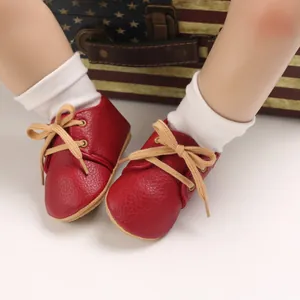Detailed close-up of red leather infant walker shoes with soft soles and beige laces.