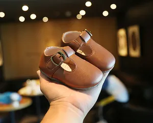 Nahaufnahme von klassischen braunen Baby-Leder-Lauflernschuhen, in einer Hand gehalten