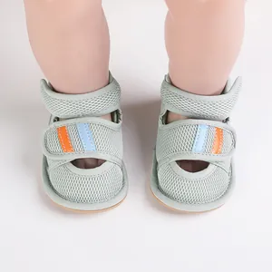 Close-up of green mesh baby walking sandals with colorful striped Velcro straps