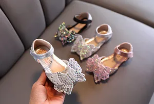 Detailweergave van elegante prinsessenschoenen voor meisjes met een sprankelende vlinder.