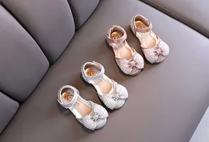 Vista detallada de zapatos de princesa para niñas en rosa y plateado con lazos de perlas.