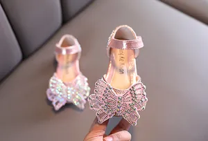 Close-up van roze meisjes prinsessenschoen met fonkelende vlinderversiering van strass steentjes