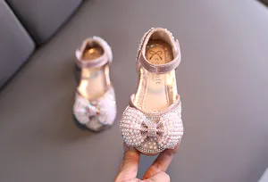 Vista detallada de zapatos de princesa rosa con lazo de perlas y pedrería fina.