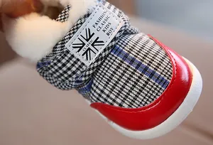 Close-up view of toddler winter snow boots with red toe cap and thick white faux fur lining.