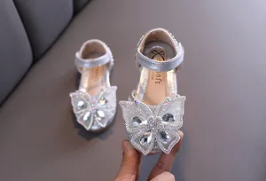 Détail de l'ornement papillon en strass sur les chaussures pailletées pour filles