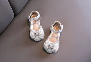 Vista detallada de zapatos de princesa plateados con lazo de perlas para niñas pequeñas