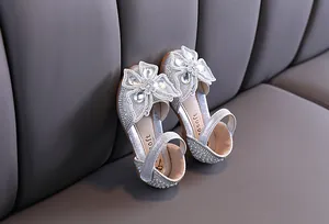 Détail de chaussures princesse argentées à paillettes pour filles avec strass papillon