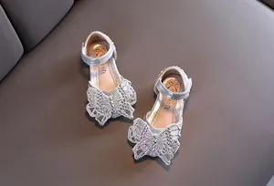 Detailopname van de glanzende zilveren meisjesschoenen met luxe strasvlinderversiering.