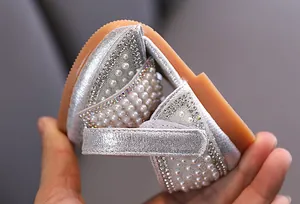Detalle de zapato de princesa plateado para niña con elegantes adornos de perlas y strass