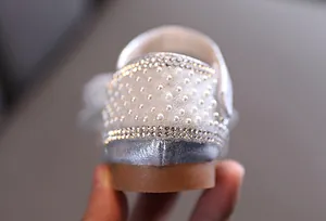 Detailopname van parel- en strassdetails op de hiel van zilveren meisjesschoenen