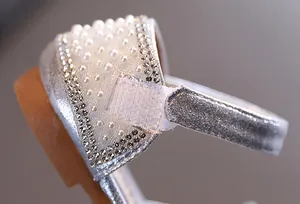 Detailopname van zilveren prinsessenschoenen voor meisjes met parels en strass steentjes