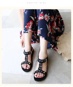 Detailed close-up view of black bohemian flat sandals with rhinestones and beads