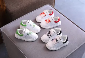 Primo piano di sneakers bianche per bambini nei colori rosso, verde e nero.