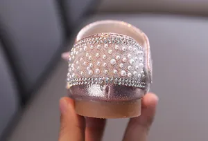 Vue détaillée des perles et des strass décoratifs sur les chaussures roses de fille