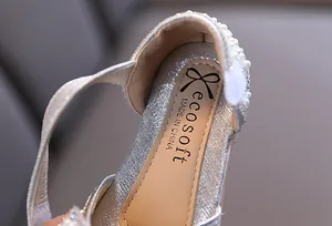 Primer plano de zapato de princesa plateado para niña con talón de perlas y marca