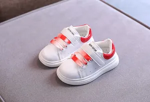 Primo piano di sneaker per bambini in pelle bianca con dettagli rossi e lacci sfumati