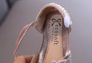 Vue rapprochée de chaussures de princesse roses à paillettes avec perles et logo
