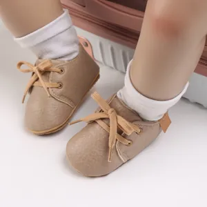 Close-up view of soft tan leather baby walking shoes with laces and white socks.