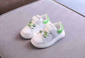 Dettaglio di sneaker in pelle bianca per bambini con accenti verdi e velcro
